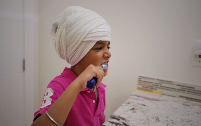 Young child in a turban practicing good dental hygiene by brushing teeth indoors.