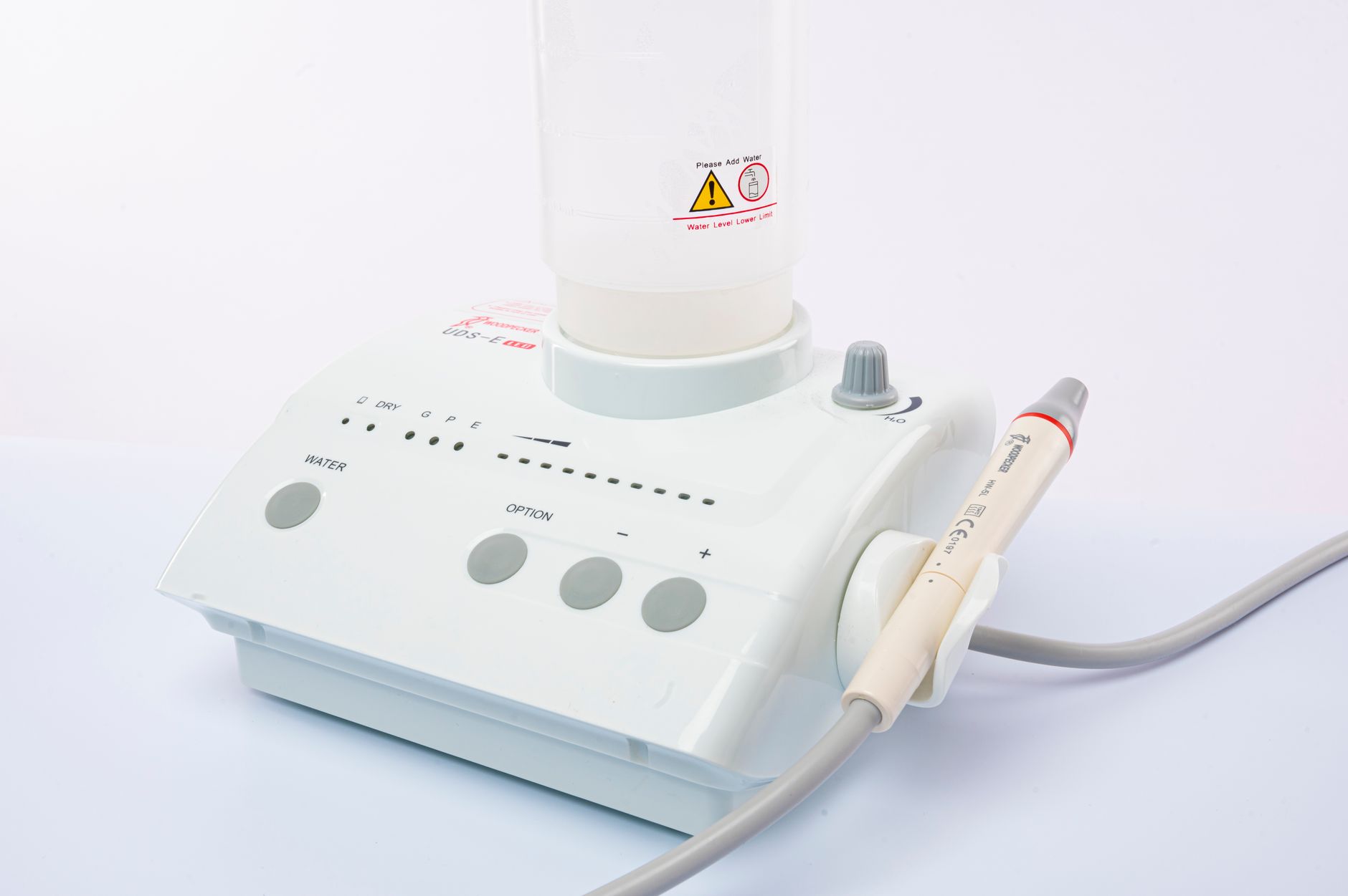Close-up of a dental ultrasonic scaler with water supply on a white background.