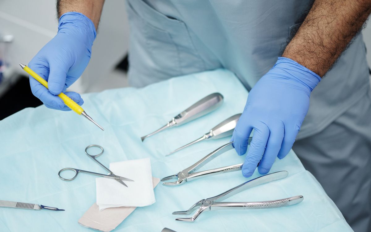 Close-up of a dental professional's hands with tools and gloves in a clinic setting.