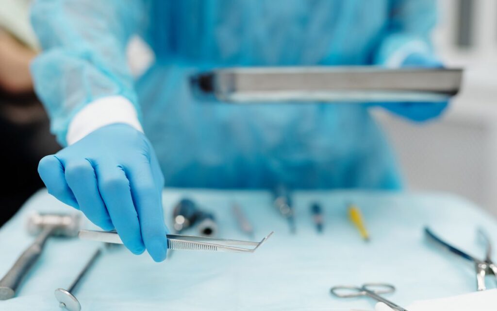 Blue-gloved hand handles surgical tools in a medical setting, focusing on precision and cleanliness.