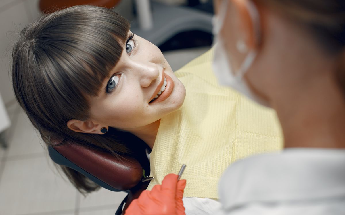 A young woman smiles while seated in a dentist chair during a dental check-up.