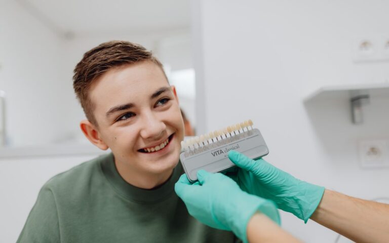 A teenager smiling during a dental shade matching procedure at a dentist office.
