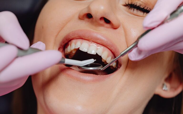 Smiling woman at dentist with tools for dental exam, highlighting dental care.