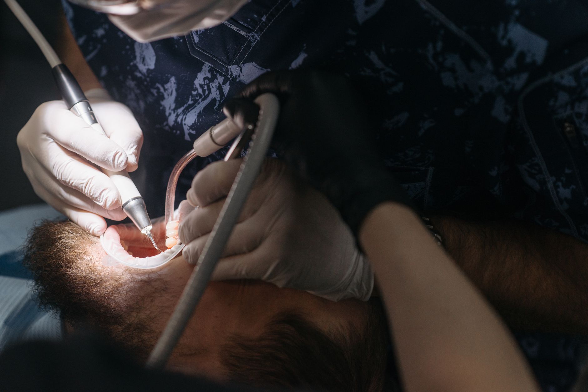 Dentist performing a procedure on a patient with dental tools inside a modern clinic.