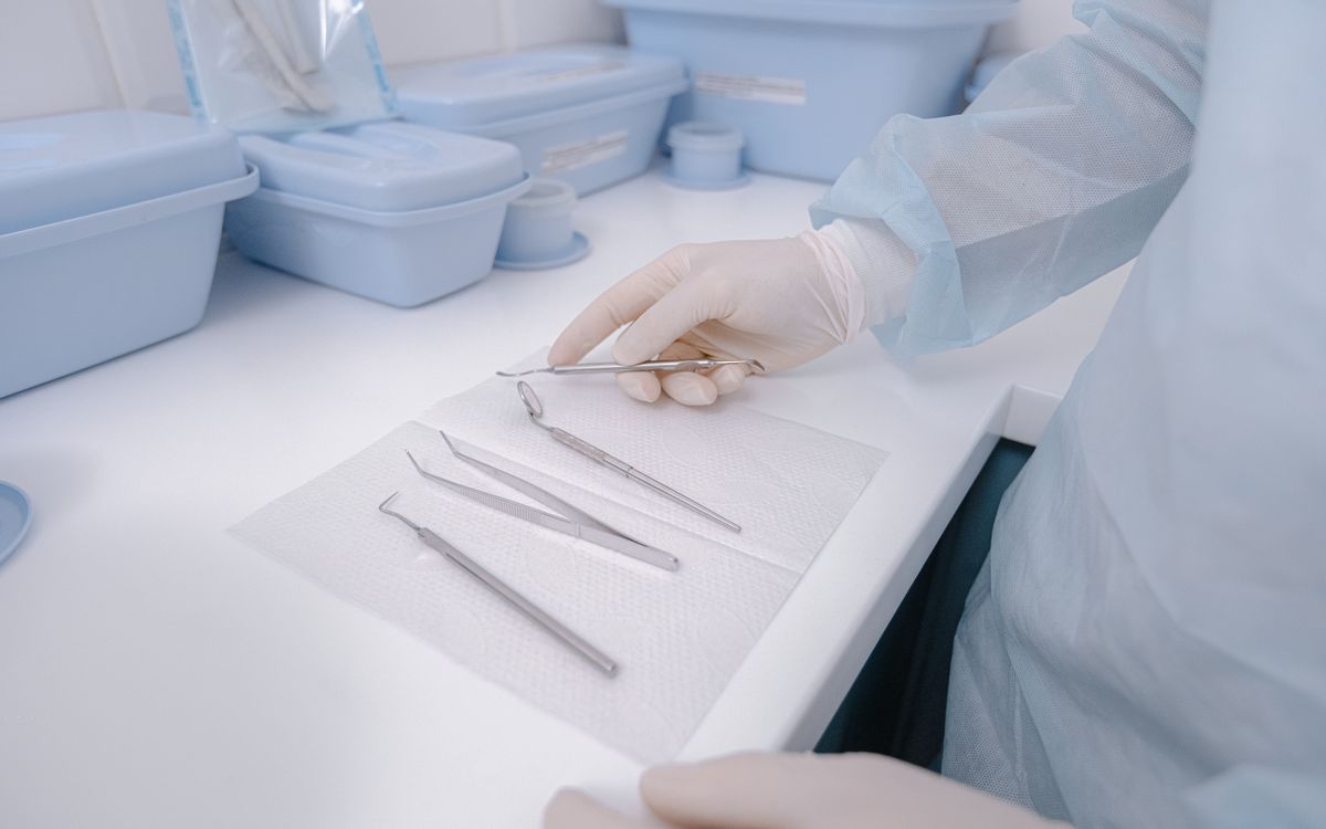 Close-up of dental tools on a table with a dentist in surgical gloves, showcasing a clean healthcare environment.