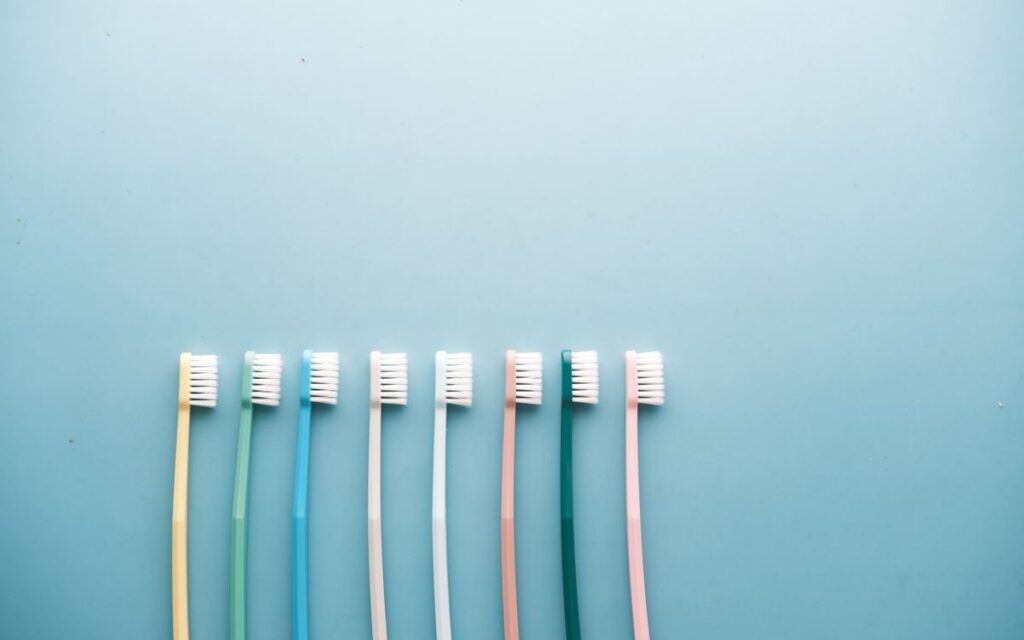An assortment of colorful toothbrushes arranged on a vibrant blue background in a minimalist style.