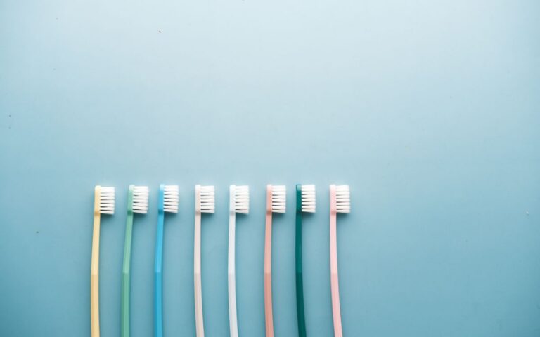 An assortment of colorful toothbrushes arranged on a vibrant blue background in a minimalist style.