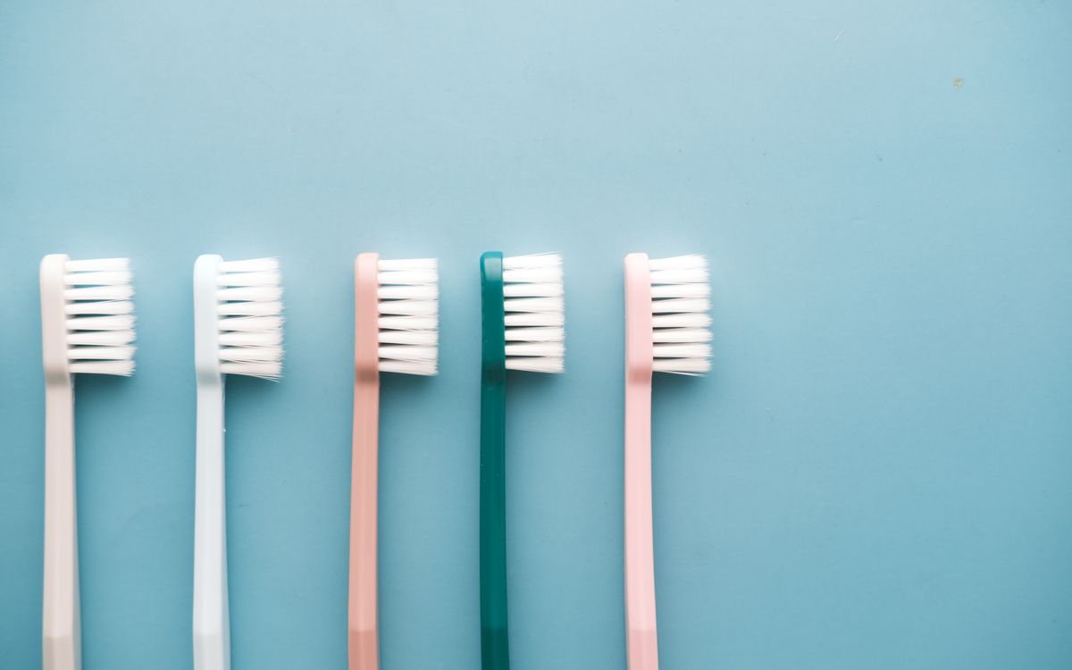 A row of five colorful toothbrushes arranged on a blue background, perfect for dental care themes.