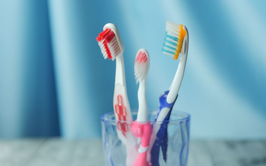 A trio of vibrant toothbrushes in a glass on a blue background, emphasizing dental hygiene.