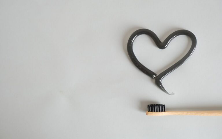 Charcoal toothpaste shaped as a heart with bamboo toothbrush on gray background. Ideal for eco-friendly dental care imag