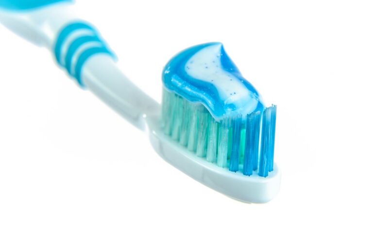 Detailed close-up image of a toothbrush with vibrant blue toothpaste for dental hygiene.