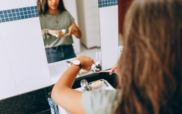 Teen girl brushing teeth in a modern bathroom, emphasizing daily hygiene routine.