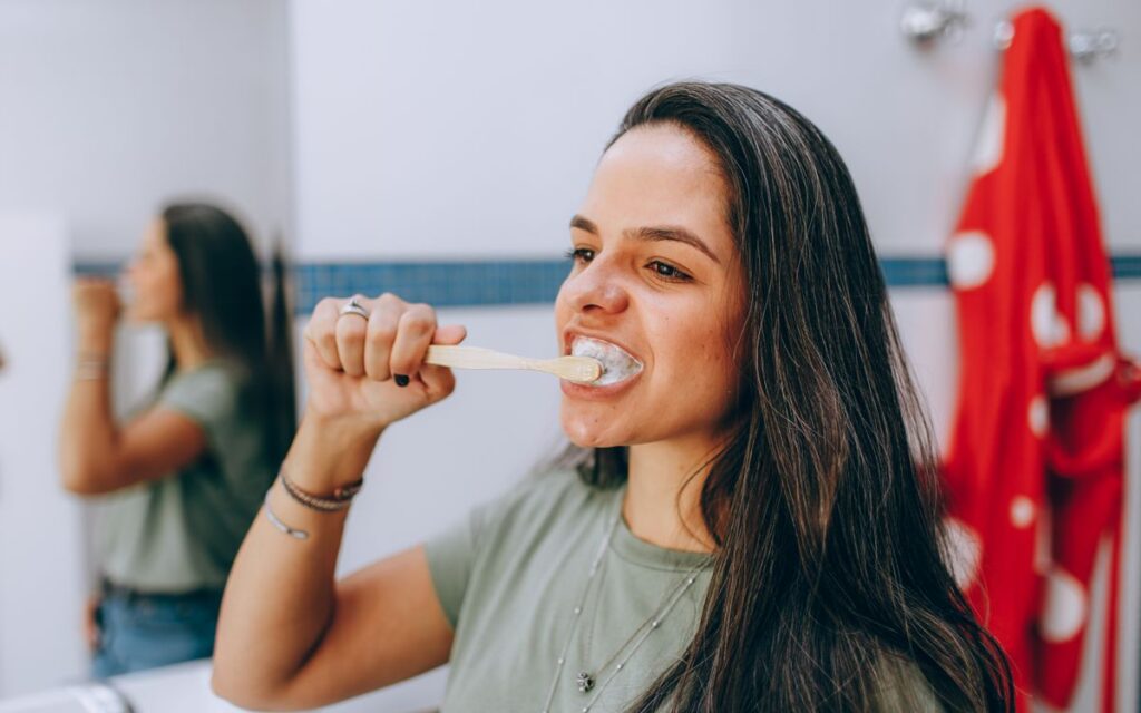 Young woman brushing teeth with toothbrush in a modern, bright bathroom. Focus on oral health care and hygiene.