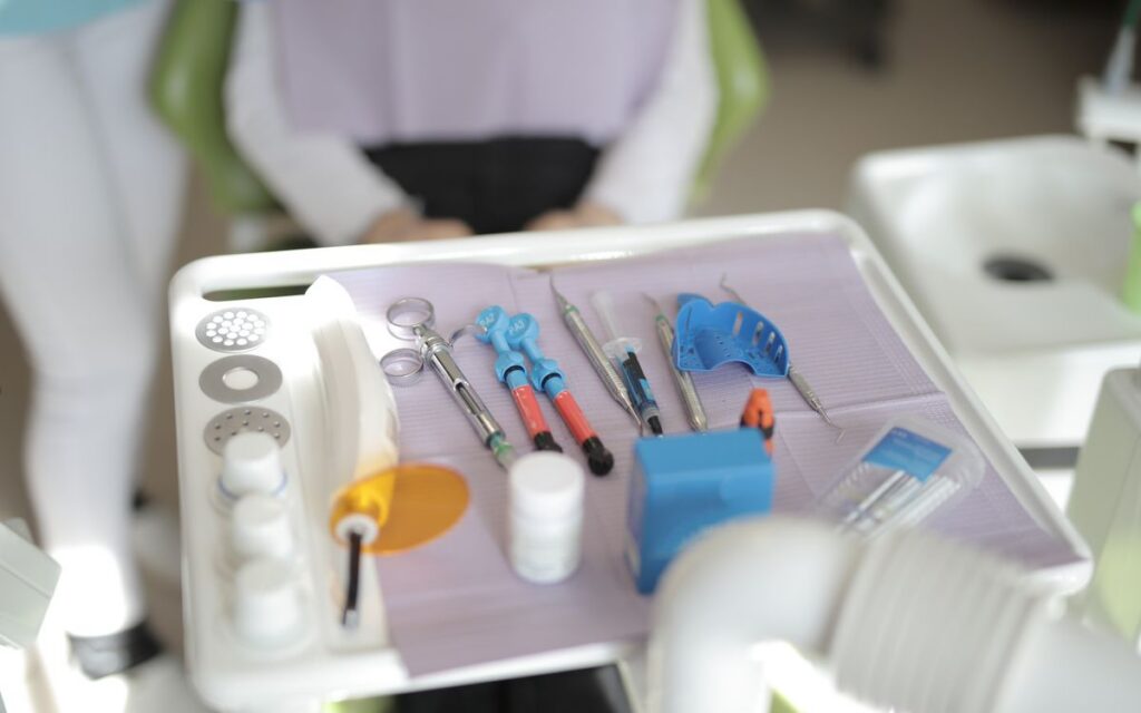 From above view of various modern medical instruments placed on tray near chair in modern room in clinic