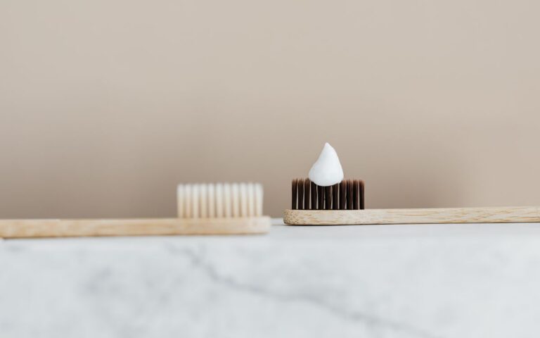 Close-up of a bamboo toothbrush with toothpaste in a minimalist setting.
