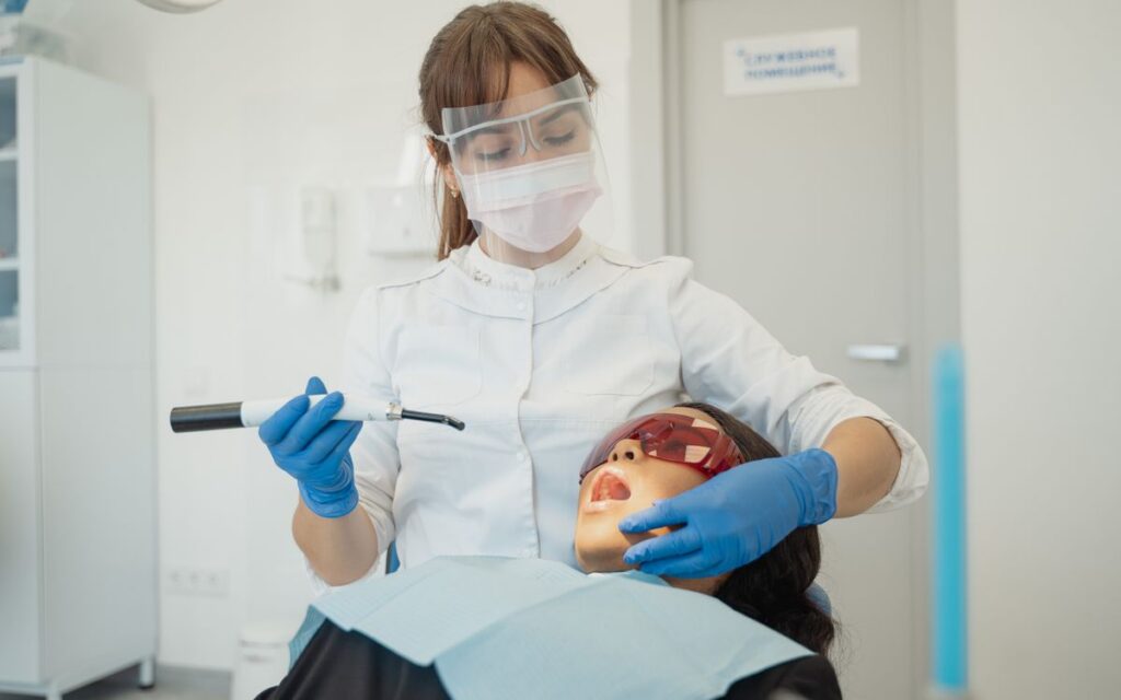A female dentist using curing light on a patient in a modern dental clinic.