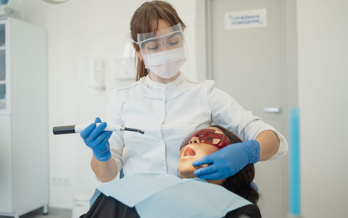 A female dentist using curing light on a patient in a modern dental clinic.