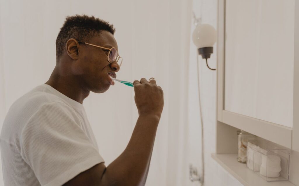 Man brushing his teeth in a bathroom, focusing on daily oral care and hygiene.