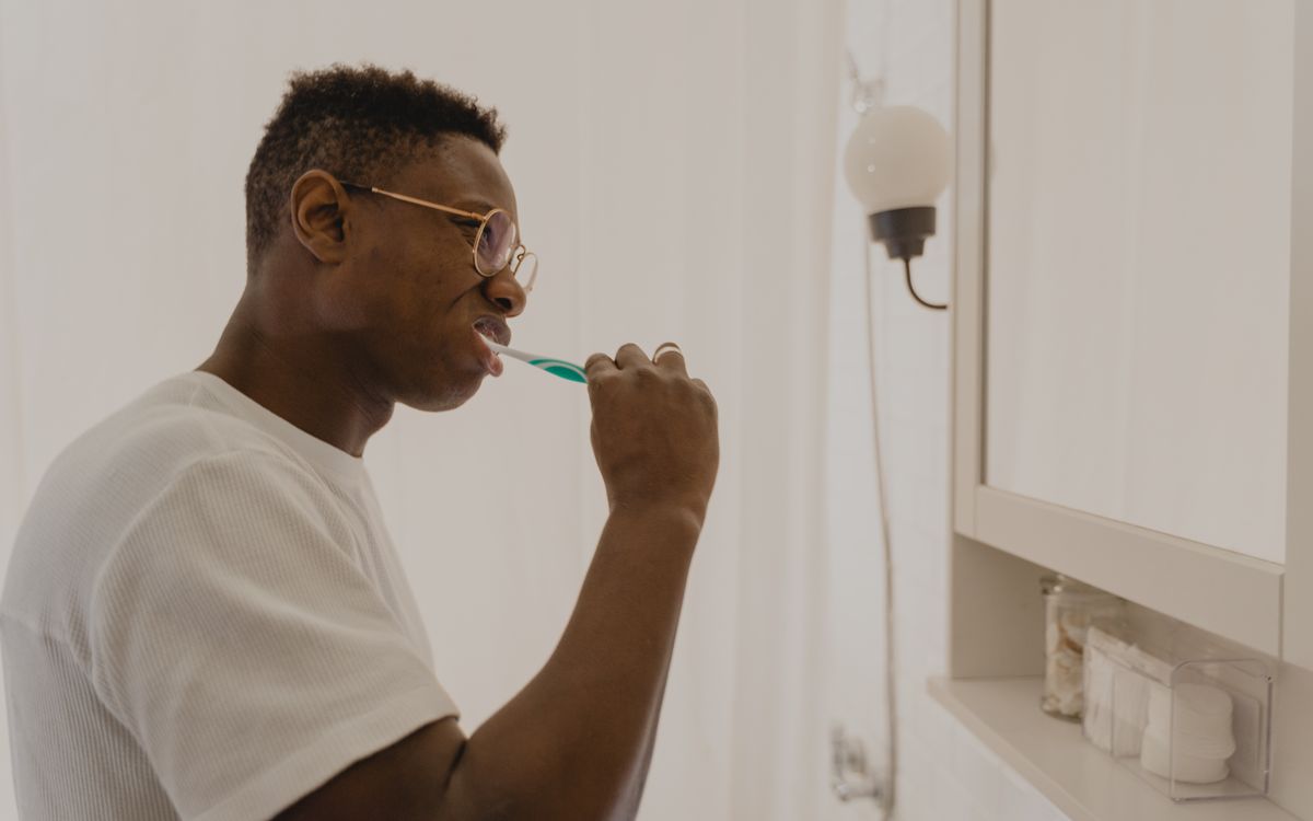 Man brushing his teeth in a bathroom, focusing on daily oral care and hygiene.