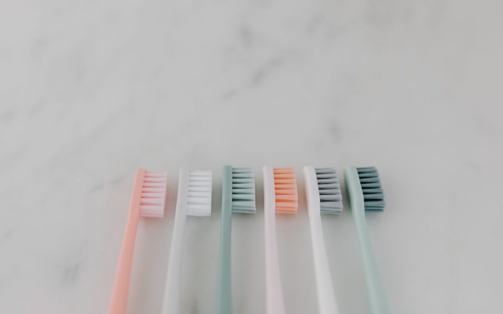 A row of colorful pastel toothbrushes aligned on a smooth marble surface.
