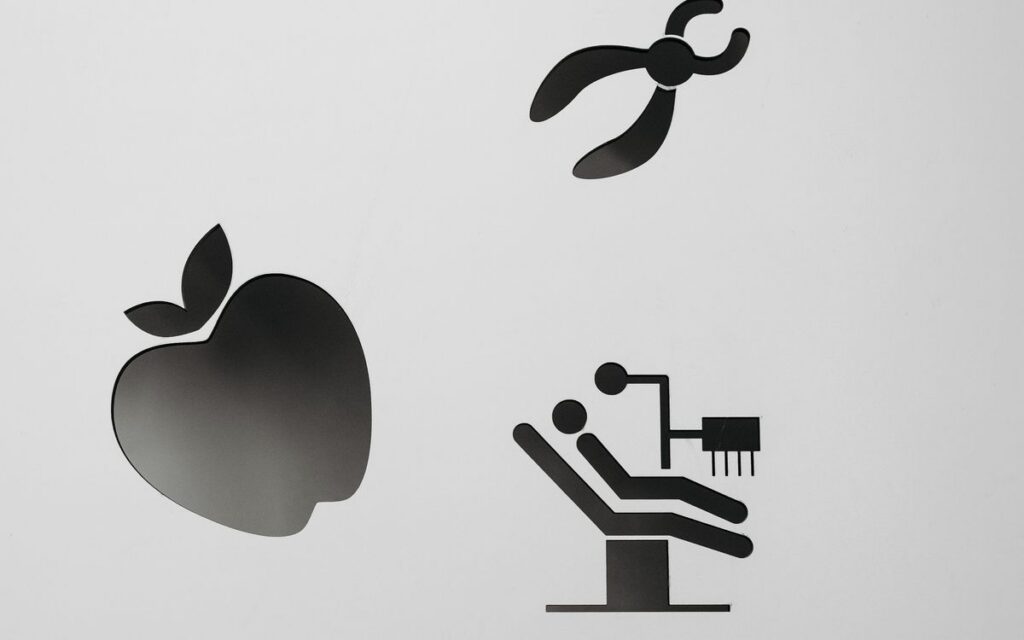 Black and white dental icons including apple and tools on gray background.