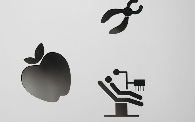 Black and white dental icons including apple and tools on gray background.