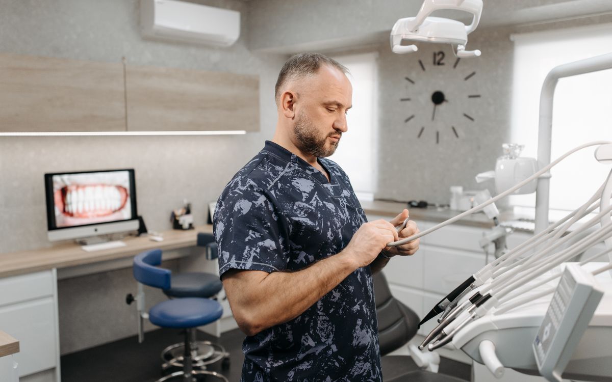 Dentist preparing dental tools in a modern dental office with equipment and patient images.