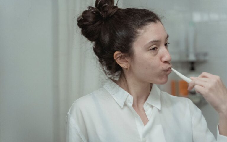 A woman brushes her teeth in the bathroom as part of her daily oral hygiene routine.